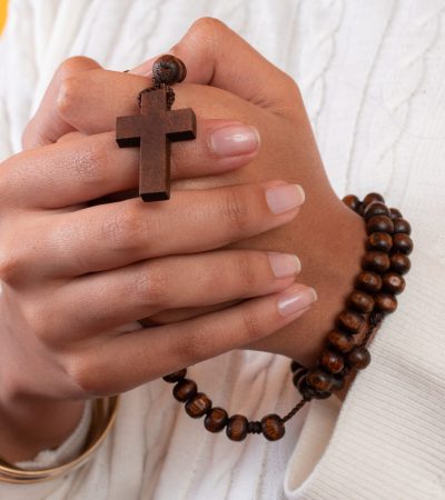 A closeup shot of a rosary with a cross in female's hands